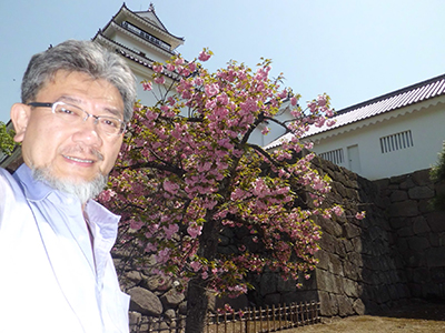 会津城と八重桜をバックにした三宅善信代表 会津城と八重桜をバックにした三宅善信代表