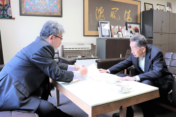 平岡英信清風学園理事長にG20諸宗教フォーラムの概要を説明する