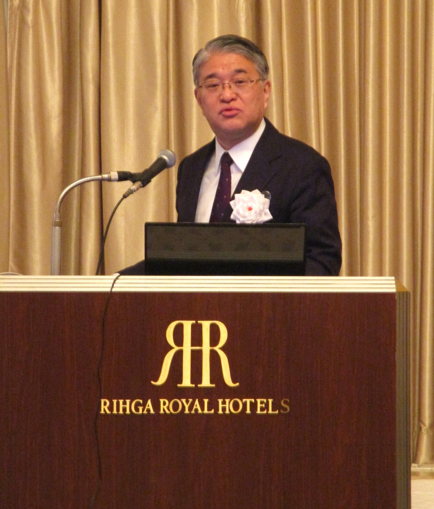 第532回国連午餐会で主催者挨拶を行う三宅善信師と講演する正木一博日銀大阪支店長